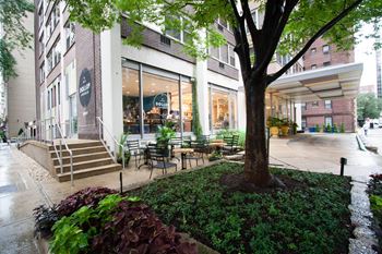 a patio with a tree and tables outside of a building